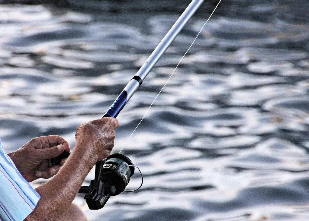 Um pescador bem equipado e organizado, pescando à beira de um rio.