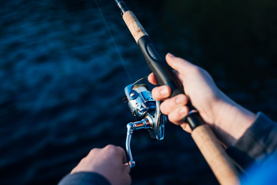 Uma pessoa segurando uma carretilha de pesca, com foco nas mãos e na carretilha